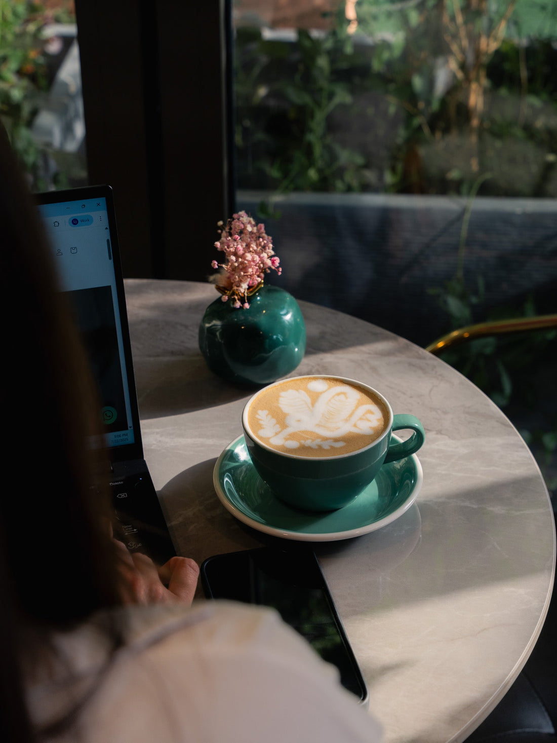 a picture of a woman working in auro deerfields cafe showing the mug of coffee latte with latte art from auro cafe at deerfields mall abu dhabi branch