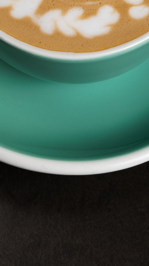 A photo showing a section of Auro Coffee mug with Latte in it